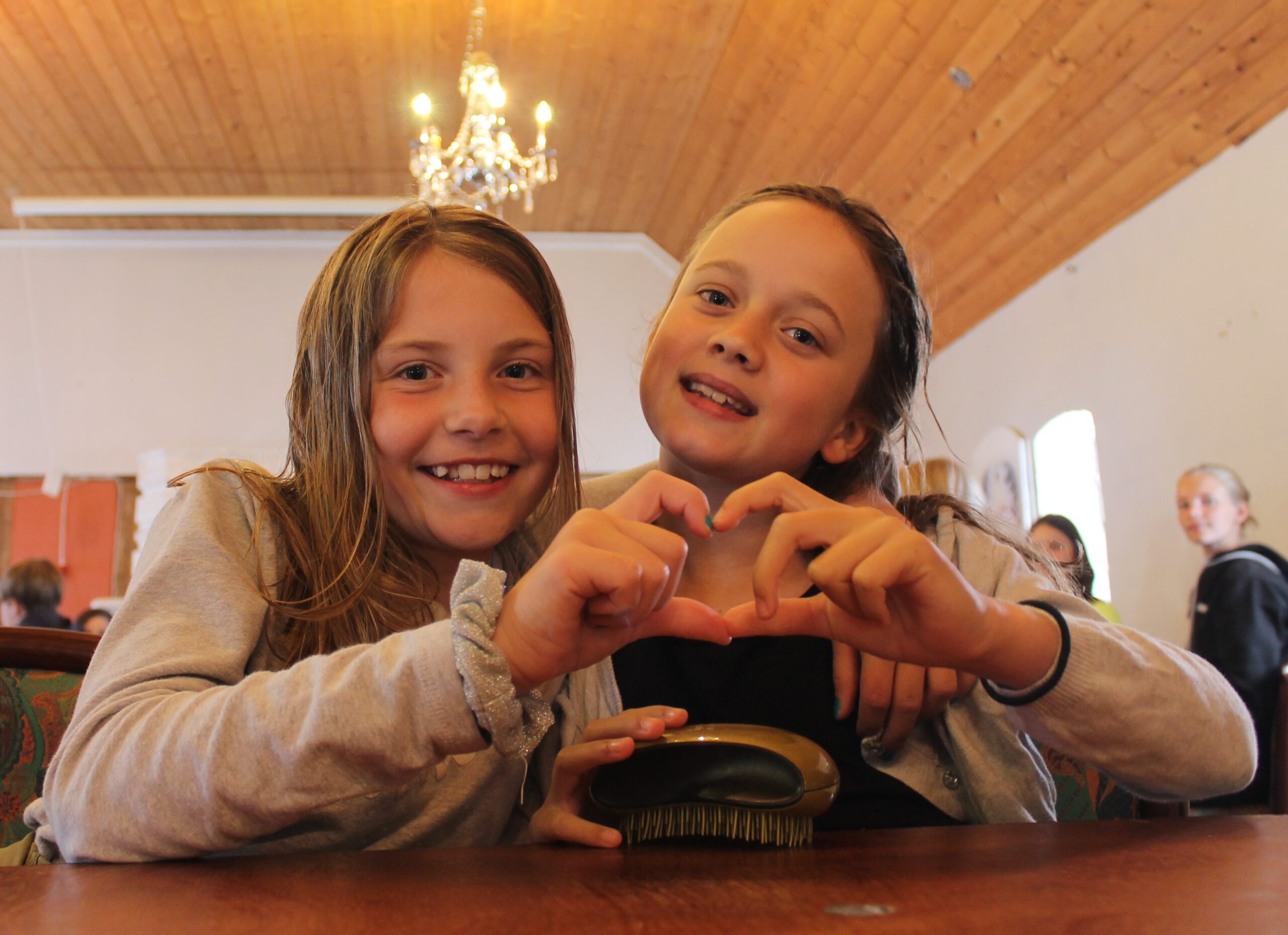 To glade børn danner et hjerte med hænderne under en fælles aktivitet støttet af HJMV Fonden.